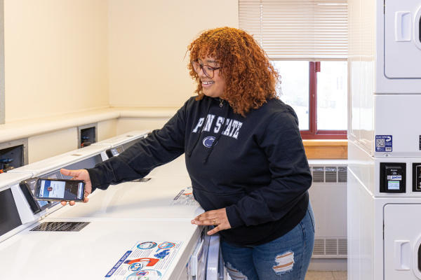 student using phone to pay for laundry