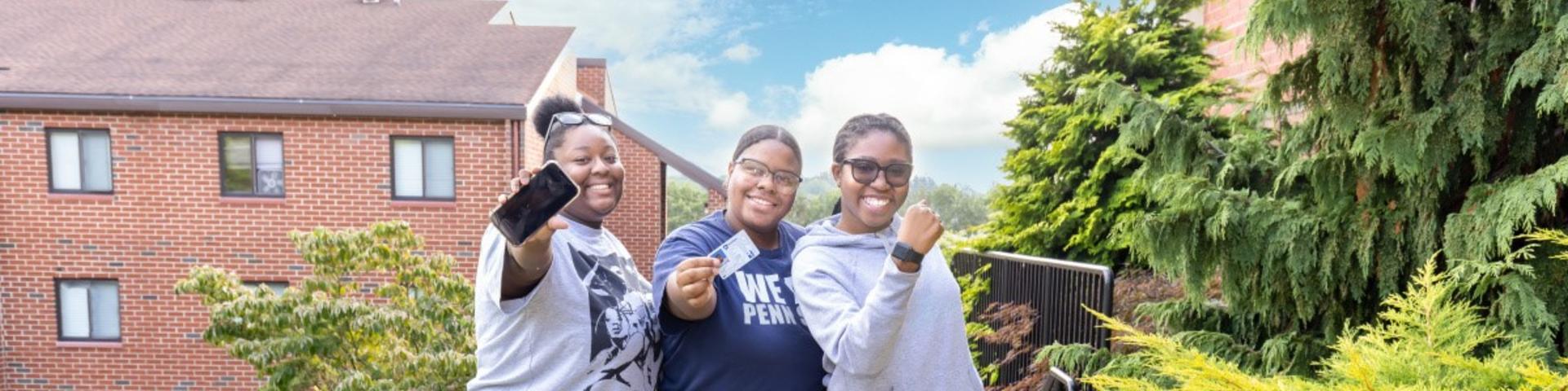 three people holding forms of Penn State identification